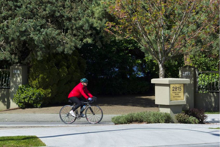  A cyclist uses the bike path that crosses the entrance to 2815 Point Grey Rd., the waterfront property of Vancouver Army and Navy CEO and socialite Jacqui Cohen.