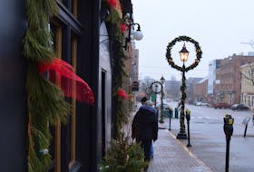 Two walkers on a recent stroll pause to check out a menu in downtown Charlottetown. The mild temperatures and bare sidewalks are expected to give way to snowdrifts beginning on Jan. 7 as 2022's first nor'easter hits P.E.I.