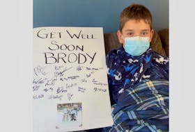 Brody Kouwenberg sits with the giant get-well card the Amherst CIBC Wood Gundy Ramblers sent to him during his battle with COVID-19. Born with a complete fetal heart block, the 11-year-old Oxford native was in his fourth season of playing minor hockey when he was hit by COVID. CONTRIBUTED PHOTO