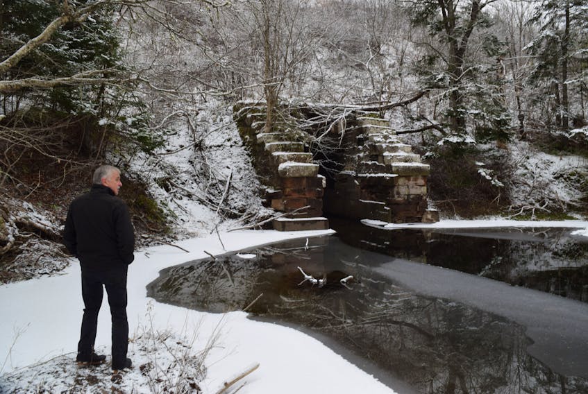 John Ashton looks at a stone culvert that was used to create a railway crossing over the Middle River.