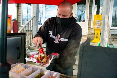 Adam Doiron, co-owner of the Beefy Weiner, adds some sauerkraut for a customer in Elmsdale on Thursday, Jan. 6, 2022.