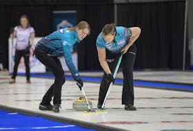 Jessie Haughian, left,  and Kristie Moore of Casey Scheidegger's rink sweep a rock at the 2022 Sentinel Storage Alberta Scotties Tournament of Hearts in Grande Prairie. 