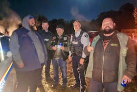 Two RCMP members pose for a photo with a trio of men at a so-called "freedom fighters" event Oct. 8, 2022, in Nictaux, N.S. The RCMP member on the right is wearing a thin blue line patch above the word 'police' on his uniform. - Facebook