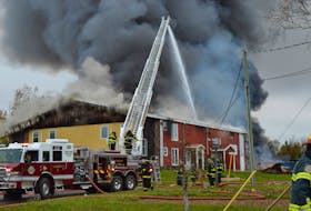 Members of the Charlottetown and Cross Roads fire departments battle smoke and flames billowing out of a building on Mason Road in Stratford on Oct. 17.