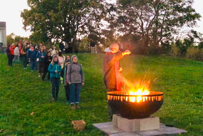 Participants release prayers by dropping ceremonial tobacco into a fire during a Truth and Reconciliation Day event Friday, Sept. 30, at Pippy Park in St. John's.