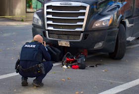 A police officer takes photos after an 18-wheeler struck a person on a mobility scooter at the intersection of Hollis Street and Terminal Road on Friday, Oct. 21, 2022. Ryan Taplin - The Chronicle Herald