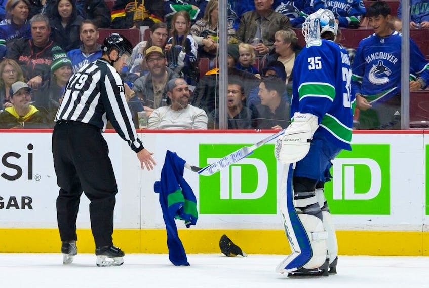 Canucks goalie Thatcher Demko picks up a jersey that was thrown onto the ice by a fan in the third period during their NHL game against the Buffalo Sabres at Rogers Arena Oct. 22, 2022. Buffalo won 5-1.