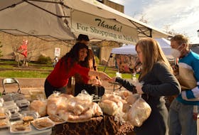 Nazly Farhady, left, hands Tammy Gaudet some fresh bread from Nick's Bakery Deli and Convenience at Farm Day in the City Oct. 23.  Alison Jenkins • The Guardian