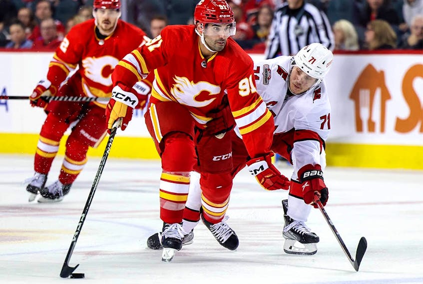  Nazem Kadri #91 of the Calgary Flames and Jesper Fast #71 of the Carolina Hurricanes battle for the puck in third period of the game at Scotiabank Saddledome on October 22, 2022 in Calgary, Alberta, Canada.