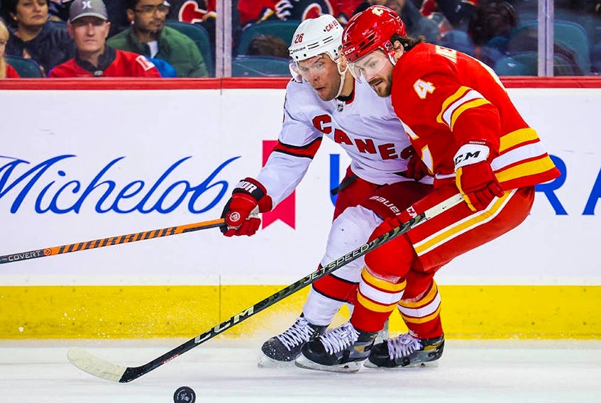  Oct 22, 2022; Calgary, Alberta, CAN; Calgary Flames defenceman Rasmus Andersson (4) and Carolina Hurricanes center Paul Stastny (26) battle for the puck during the third period at Scotiabank Saddledome.