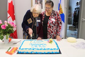 Elsie Roberts cuts a cake, with Jessie Foy looking, to celebrate 100 years of the Colchester Hospital Auxiliary.