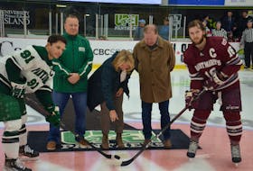 Melissa James drops the puck for a ceremonial faceoff between captains Troy Lajeunesse, left, of the UPEI Panthers and Keith Getson of the Saint Mary’s Huskies. Melissa and her brothers, Todd, left, and Mike, represented the James family honouring their father, Harry James, before a recent Atlantic University Sport men’s hockey game. The Panthers announced the team’s 50-50 draw has been renamed the Harry James 50-50 Draw to honour and recognize his many years as a ticket seller and program supporter. Jason Simmonds • The Guardian
