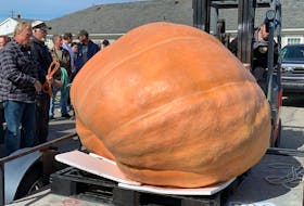 John Porter (left) watches as his prize winning 1,400 pound pumpkin is unloaded from his trailer at the annual Clark’s Harbour Pumpkin and Squash Weigh-in on Oct. 2. KATHY JOHNSON