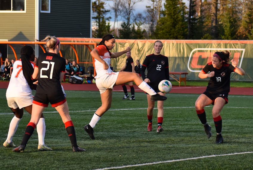 Alliyah Rowe of the Cape Breton Capers, middle, kicks the ball towards the net during Atlantic University Sport action against the New Brunswick Reds at Ness Timmons Field in Sydney, Thursday. Cape Breton won the game 3-2. JEREMY FRASER/CAPE BRETON POST.