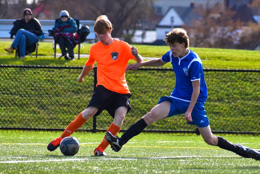 Chase Doucette of the Memorial Marauders, left, looks to make a pass as he's pressured by Shane Greencorn of the Sydney Academy Wildcats during Cape Breton High School Soccer League boys' action at Open Hearth Park in Sydney, Wednesday. Sydney Academy won the game 6-1. JEREMY FRASER/CAPE BRETON POST.