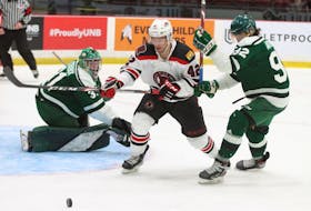 The UNB Reds’ Cole MacKay, 42, and UPEI Panthers’ Danil Antropov, 92, focus on the puck to the right of UPEI goaltender Lucas Fitzpatrick during an Atlantic University Sport men’s hockey game in Fredericton, N.B., on Oct. 7. The Reds won the game 5-2. UNB Athletics Photo • Special to The Guardian