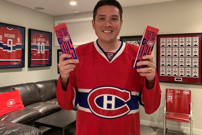 Canadiens fan Rob Hing in his Calgary home holding the season-ticket package he received after spending 10 years on the team's waiting list.