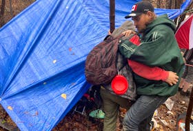 Daniel Hovey, right, gets a hand moving around his tent at a homeless encampment near Flinn Park in Halifax. Hovey is blind and has been living at the location since the summer.