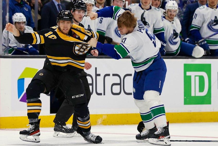 Boston Bruins' A.J. Greer (10) fights with Vancouver Canucks' Vasily Podkolzin during the first period of an NHL hockey game Sunday, Nov. 13, 2022, in Boston.
