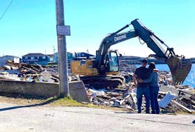 Lloyd and Peggy Savery look at the pile of rubble that was once their home. The blue house right by the ocean in Port aux Basques was destroyed by post-tropical storm Fiona. – Photo by Tammy Kettle