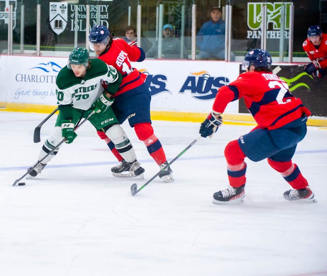 Drake Pilon, 70, controls the puck as the UPEI Panthers forward is defended closely by the Acadia Axemen’s Corson Hopwo and Brendan Tomilson, right, in an Atlantic University Sport (AUS) men’s hockey game at MacLauchlan Arena on Nov. 16. Pilon scored the winning goal on a first-period power play in the Panthers’ 2-0 victory. Janessa Hogan Photo • Courtesy of UPEI Athletics