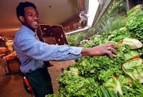 Kevin Brown stocks the shelves with green leaf lettuce at Pete's Frootique in Bedford on Friday. (Peter Parsons/Herald Photo)