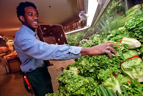Kevin Brown stocks the shelves with green leaf lettuce at Pete's Frootique in Bedford on Friday. (Peter Parsons/Herald Photo)
