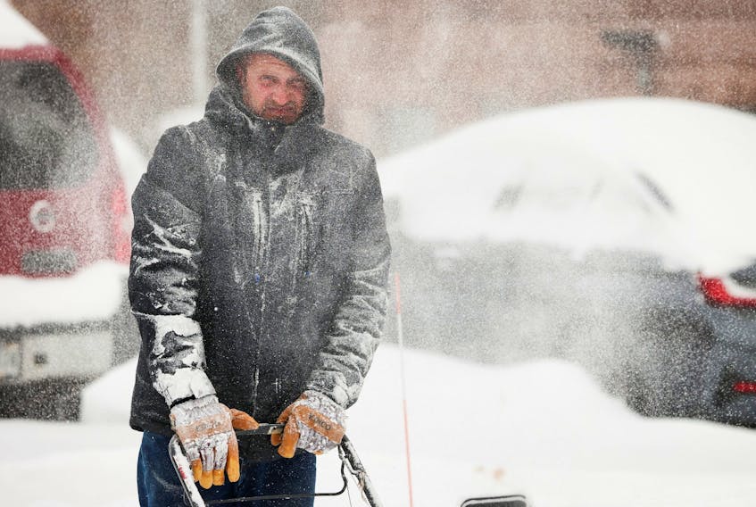 Man uses snowblower during a snowstorm as extreme winter weather hits Buffalo.