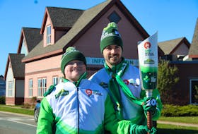 After the first segment of the Cavendish Farms Torch Relay in Borden-Carleton, torchbearer Jack Pickering passes the Canada Games Roly MccLenahan Torch to Jared Murphy. – Kristin Gardiner