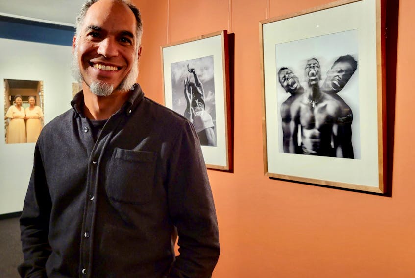 Charles Campbell, curator of the While Black exhibit, stands in front of photographs by Island photographer Robin Gessy Gislain Shumbusho at the Confederation Centre of the Arts on Nov. 18. Logan MacLean • The Guardian