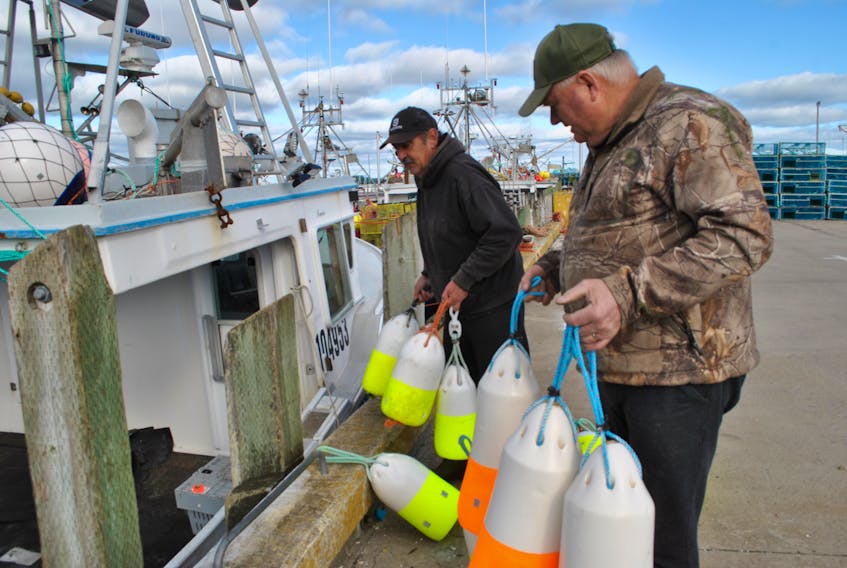 Fishing boat captain Irvine Quinlan and one of his deckhands carry buoys to be loaded aboard the Danielle & Angela at the West Head wharf on Cape Sable Island. KATHY JOHNSON