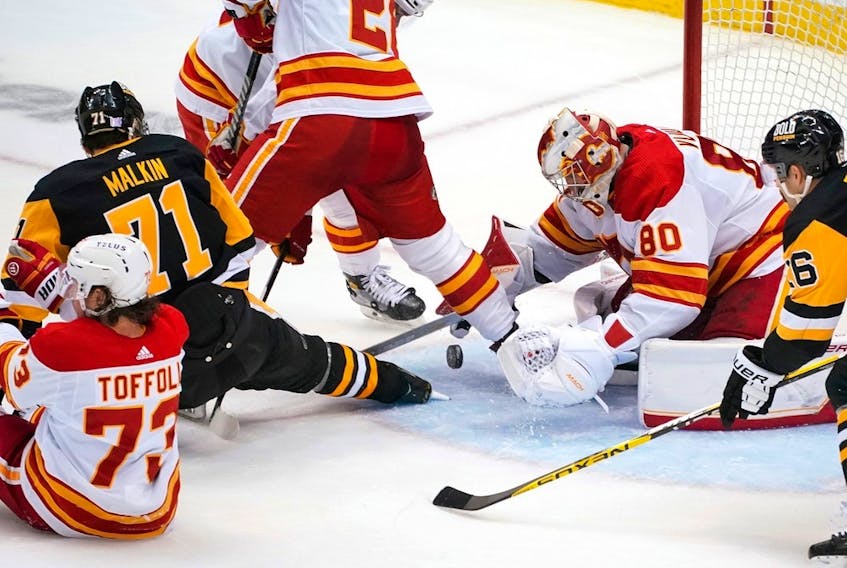 Calgary Flames goaltender Dan Vladar covers the puck as Pittsburgh Penguins forward Evgeni Malkin and Flames forward Tyler Toffoli collide at PPG Paints Arena in Pittsburgh on Wednesday, Nov. 23, 2022.