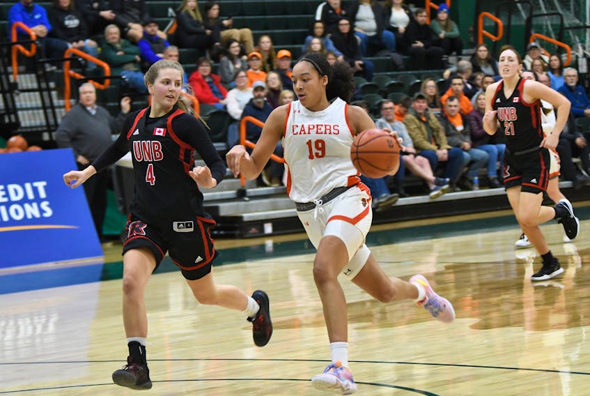 Kiyara Letlow of the Cape Breton Capers, right, takes the ball to the net as she's watched by Kylee Speedy of the New Brunswick Reds during Atlantic University Sport women's basketball action at Sullivan Field House in Sydney on Friday. Cape Breton won the game 78-74. PHOTO/VAUGHAN MERCHANT, CBU ATHLETICS.