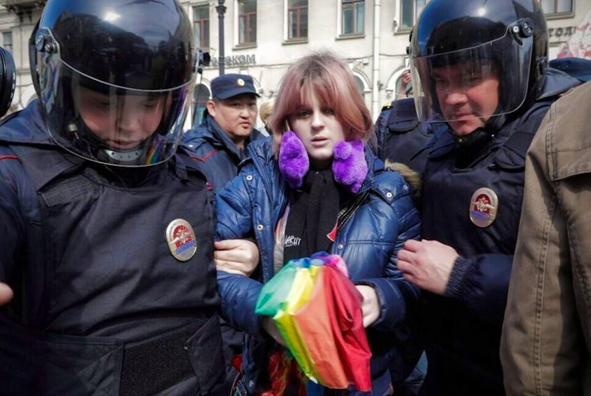 In this Monday, May 1, 2017 file photo, a gay rights activist holding a rainbow umbrella is detained by police during a rally marking May Day in downtown St. Petersburg, Russia.