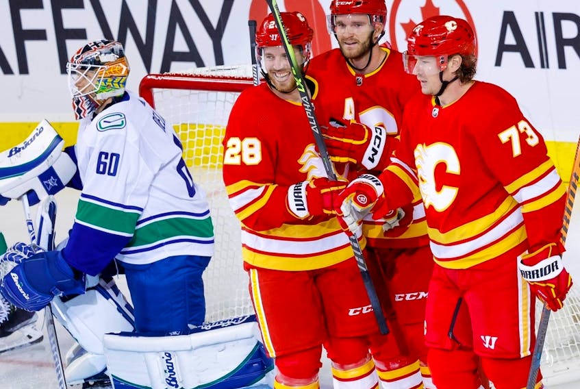 Calgary Flames forward Jonathan Huberdeau (second from right) celebrates a pre-season goal against the Vancouver Canucks with Elias Lindholm and Tyler Toffoli. The trio, who started the season skating together, have been reunited on the Flames’ first line.