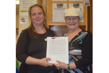 Trenton library branch assistant Thekla Altmann, left, accepts the official submission to the Beta Reader Spot program from writer Marianne Guimond White during the official program launch.