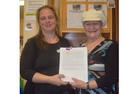 Trenton library branch assistant Thekla Altmann, left, accepts the official submission to the Beta Reader Spot program from writer Marianne Guimond White during the official program launch.