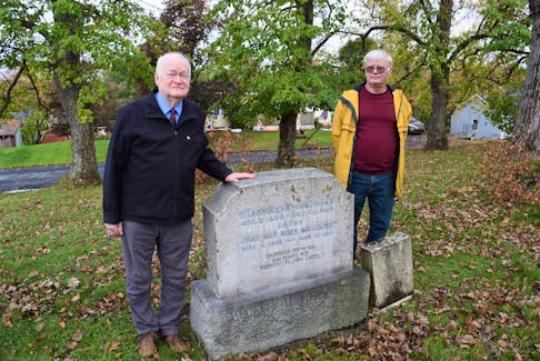 Clyde Macdonald and Murray Biggar stand by the headstone of Drummond Matheson, a First World War Flying Ace. Macdonald has had an inscription added to Matheson's headstone highlight his military accomplishments.
