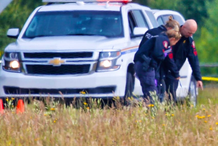  Police examine the scene west of Calgary near Highway 8 where a body was discovered on Wednesday, July 12, 2017.