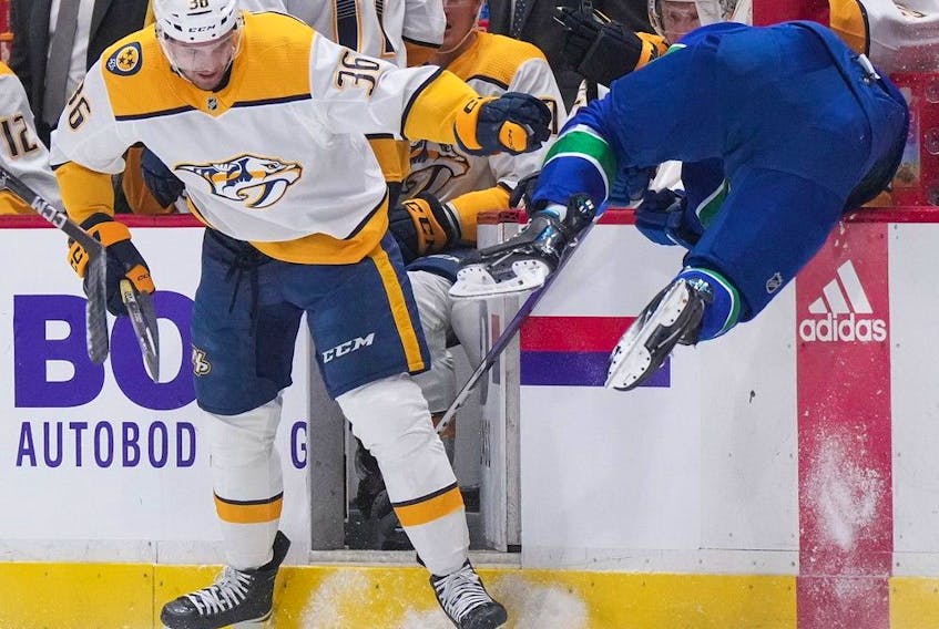  Nashville Predators’ Cole Smith, left, checks Vancouver Canucks’ Andrei Kuzmenko, of Russia, during the first period of an NHL hockey game in Vancouver, on Saturday, November 5, 2022.