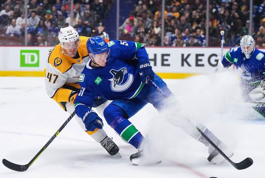  Vancouver Canucks’ Tyler Myers (57) and Nashville Predators’ Michael McCarron (47) vie for the puck during the first period of an NHL hockey game in Vancouver on Saturday night.