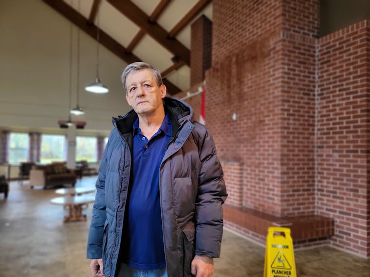 Marvin Lund stands in the common room at 501 Queen St., a publicly-owned seniors housing complex. Rain on Nov. 7 brought renewed flooding to the common area after post-tropical storm Fiona caused roof damage to the building. Stu Neatby • The Guardian
