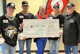 Players from the Pizza Express Northeast Eagles, Alex Carter (left), Cody Drover and Marcus Buffet (second from right) present Katie Richardson of the Canadian Red Cross a cheque for money raised by the SJJHL community with league president Jim Hare.