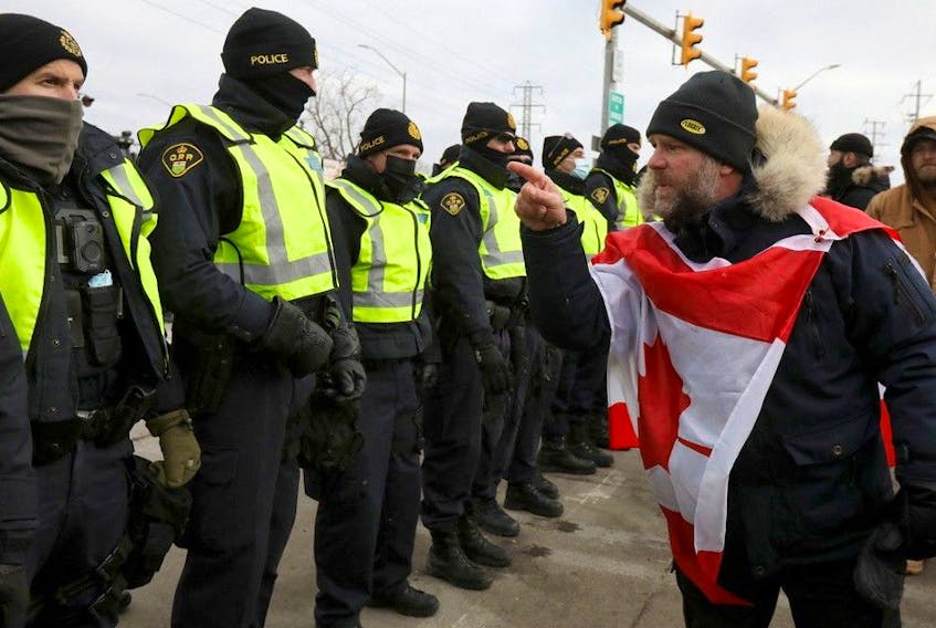 A protester gestures towards police officers, in Windsor who are starting to enforce a court order to clear truckers and supporters who have been protesting against coronavirus disease (COVID-19) vaccine mandates by blocking access to the Ambassador Bridge, which connects Detroit and Windsor, in Windsor, Ontario, February 12, 2022. REUTERS/Carlos Osorio 