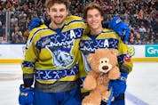 Edmonton Oil Kings Noah Boyko, left, and Rhett Melnyk collect one of the 13,111 stuffed animals donated to 630 CHED's Santas Anonymous after Boyko scored the Teddy Bear Toss goal against the Red Deer Rebels on Saturday, Dec. 10, 2022.