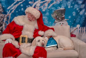 As the special time draws near for his delivery of gifts to the homes of children, Santa Claus, the wearer of one of the world’s most recognized beards, relaxes with his canine companion. Contributed