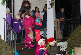A group of children sitting on the steps while singing along to Christmas carols.