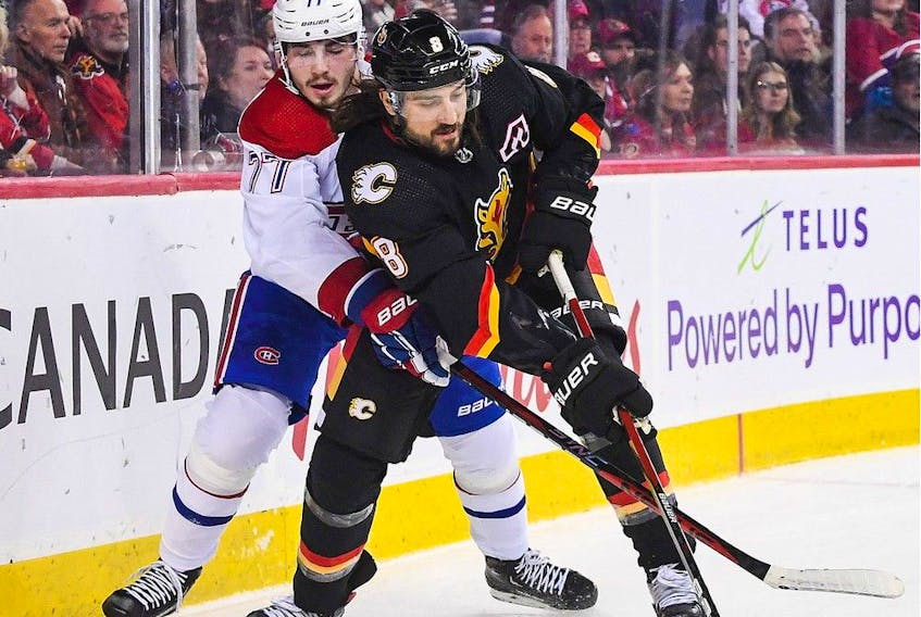 Christopher Tanev #8 of the Calgary Flames chases the puck against Kirby Dach #77 of the Montreal Canadiens during the first period of an NHL game at Scotiabank Saddledome on December 1, 2022 in Calgary, Alberta, Canada. (Photo by Derek Leung/Getty Images)