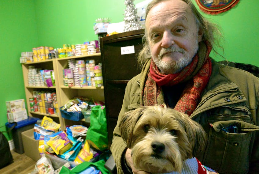 Heavenly Creatures volunteer Ivan Morgan and Buck sit near the low stock of pet food at the organization’s shelter in St. John’s. Keith Gosse • The Telegram
