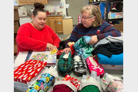 Christmas Wishes volunteers Amber Sawh, left, and Linda McCormick sort through gifts for the program that serves Springhill residents ages 17 and older and strives to make sure everyone has something under the tree on Christmas morning. DARRELL COLE